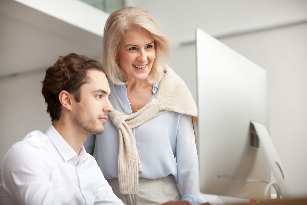 Young man and old lady in front of a computer