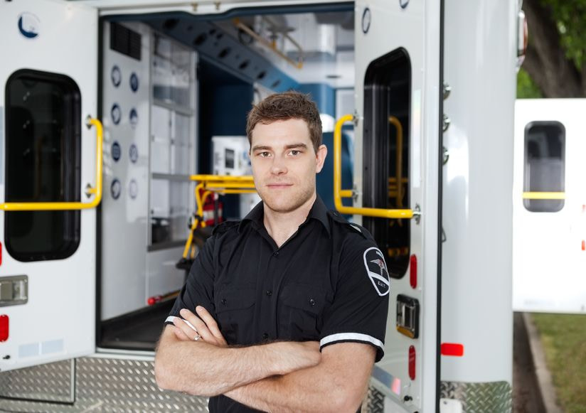 Image of EMT professional in front of the back of an ambulance vehicle